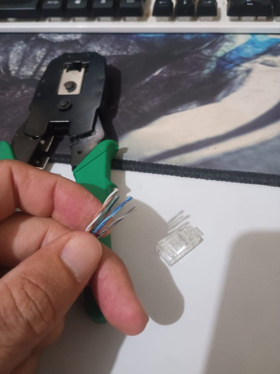 Fios prontos para a crimpagem ao lado do conector RJ45 e do alicate